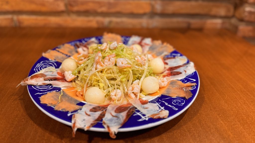 una ensalada con jamón, trocitos de melón y gambas